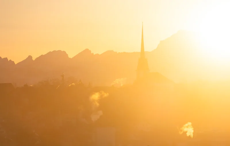Kirchturm und berge im goldenen morgenlicht
