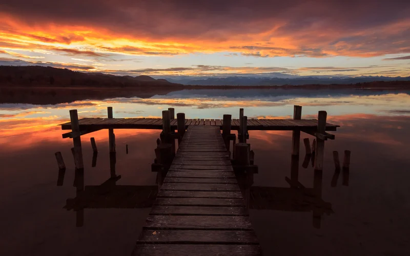 Bootssteg am see unter rotem abendhimmel