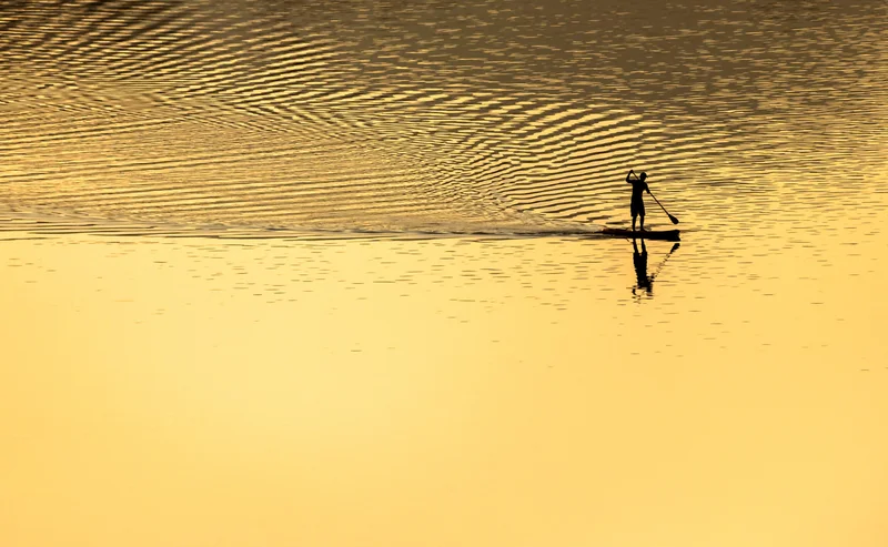 Stand up paddler auf goldenem wasser
